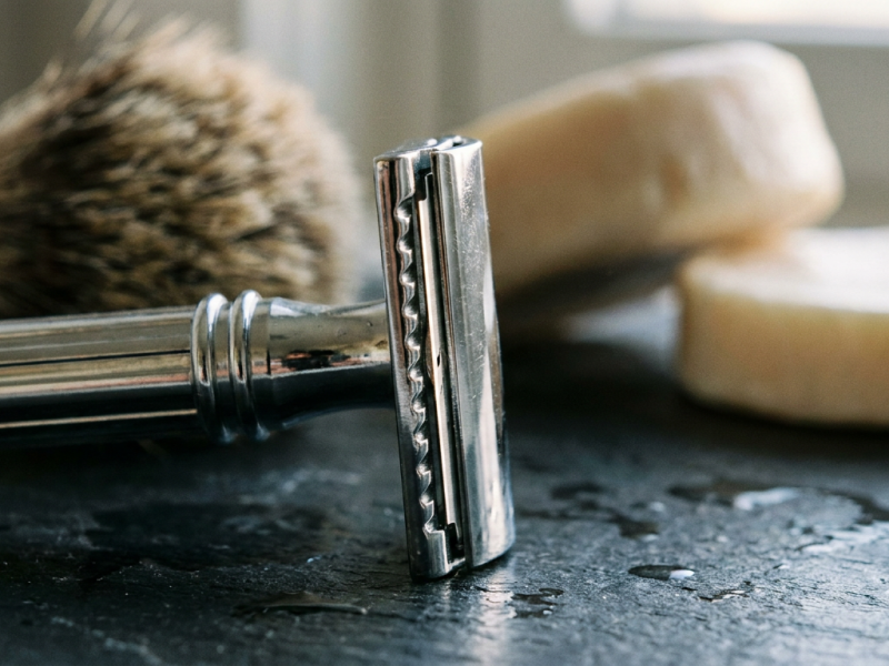 Astra Superior Platinum double edge blades stacked beside a chrome safety razor on dark slate