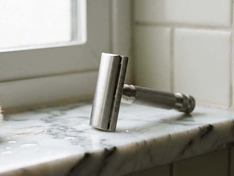 Henson AL13 machined aluminum safety razor standing upright on a marble bathroom shelf