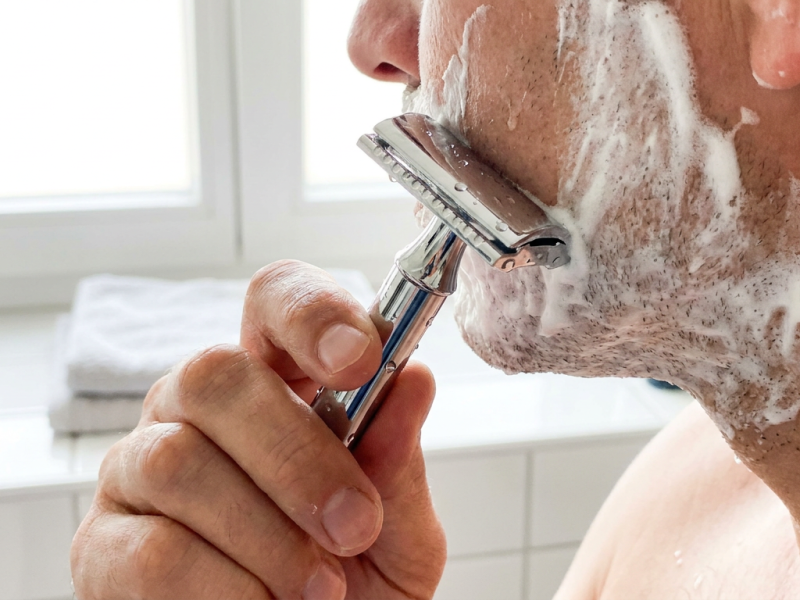 Correct safety razor angle shown against a lathered cheek during a shave