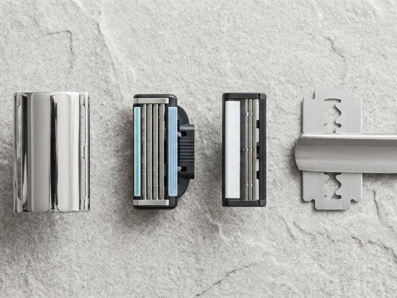 Double edge razor blades in paper wrappers beside an open safety razor