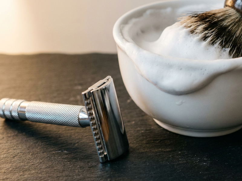 Merkur 34C safety razor with short knurled handle resting beside a lather bowl on slate